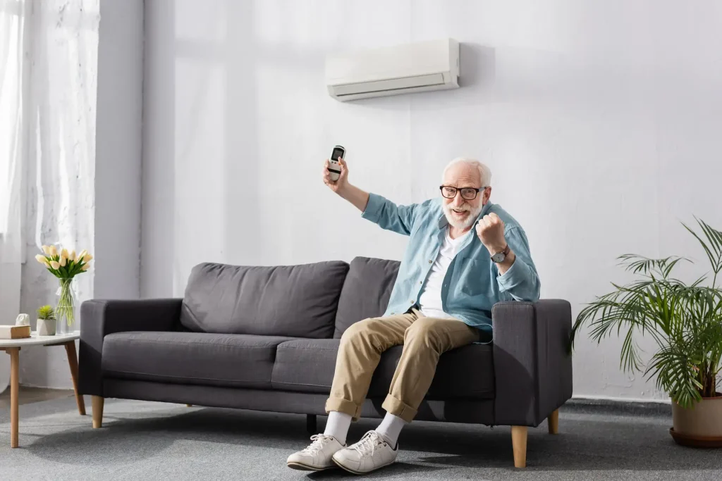 homme d'âge mûr content de sa clim réversible posée dans son salon